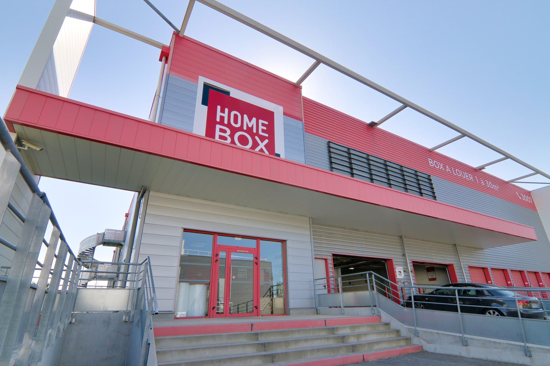 Façade rouge et grise avec auvent et enseigne lumineuse, HOMEBOX Nîmes, Place André Bazile, Zac du Mas de Vignolles à Nîmes