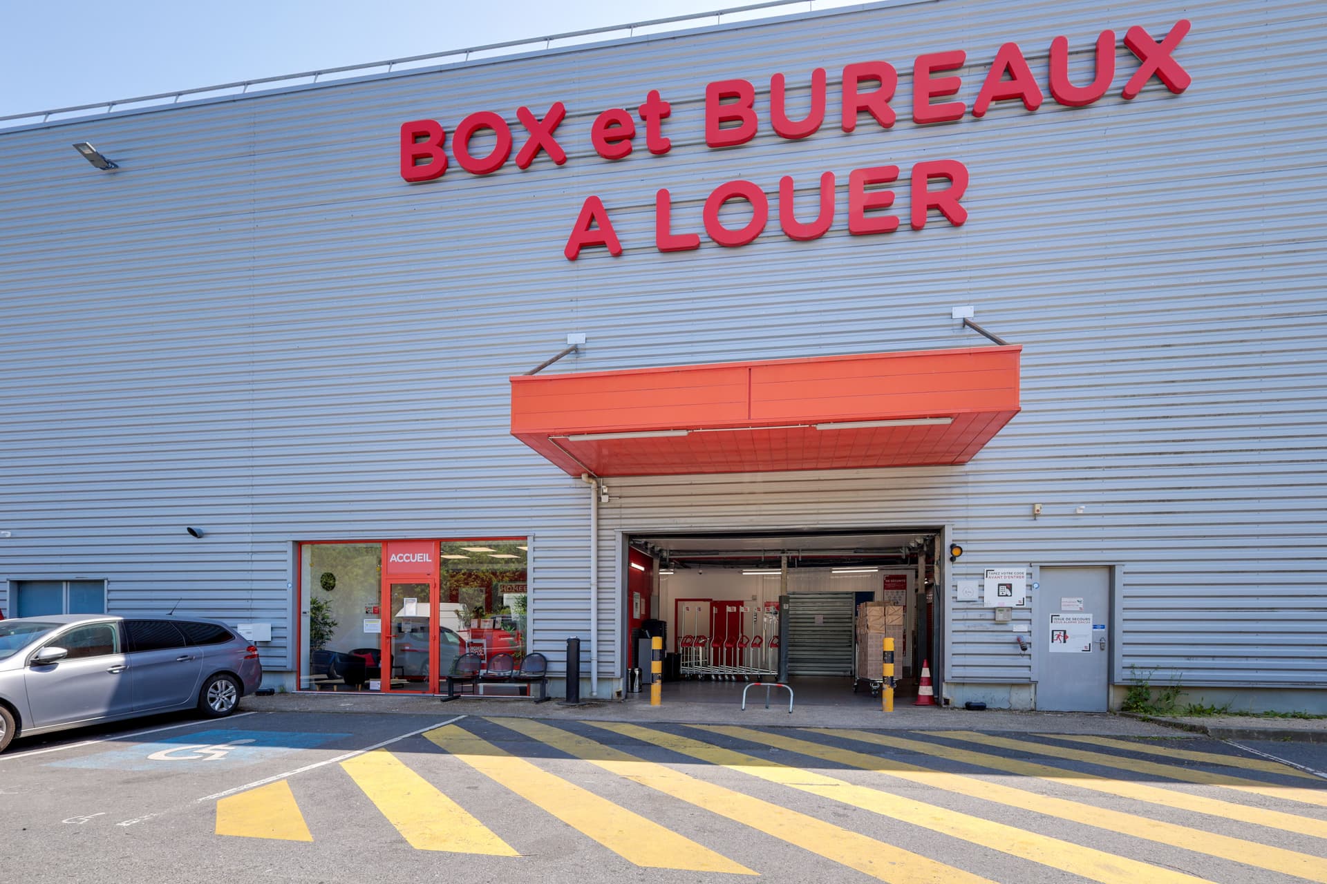 Façade avec enseigne Box et bureaux à louer et entrée accueil rouge, HOMEBOX Roissy, 383 rue de la Belle Etoile Parc des Nations à Roissy