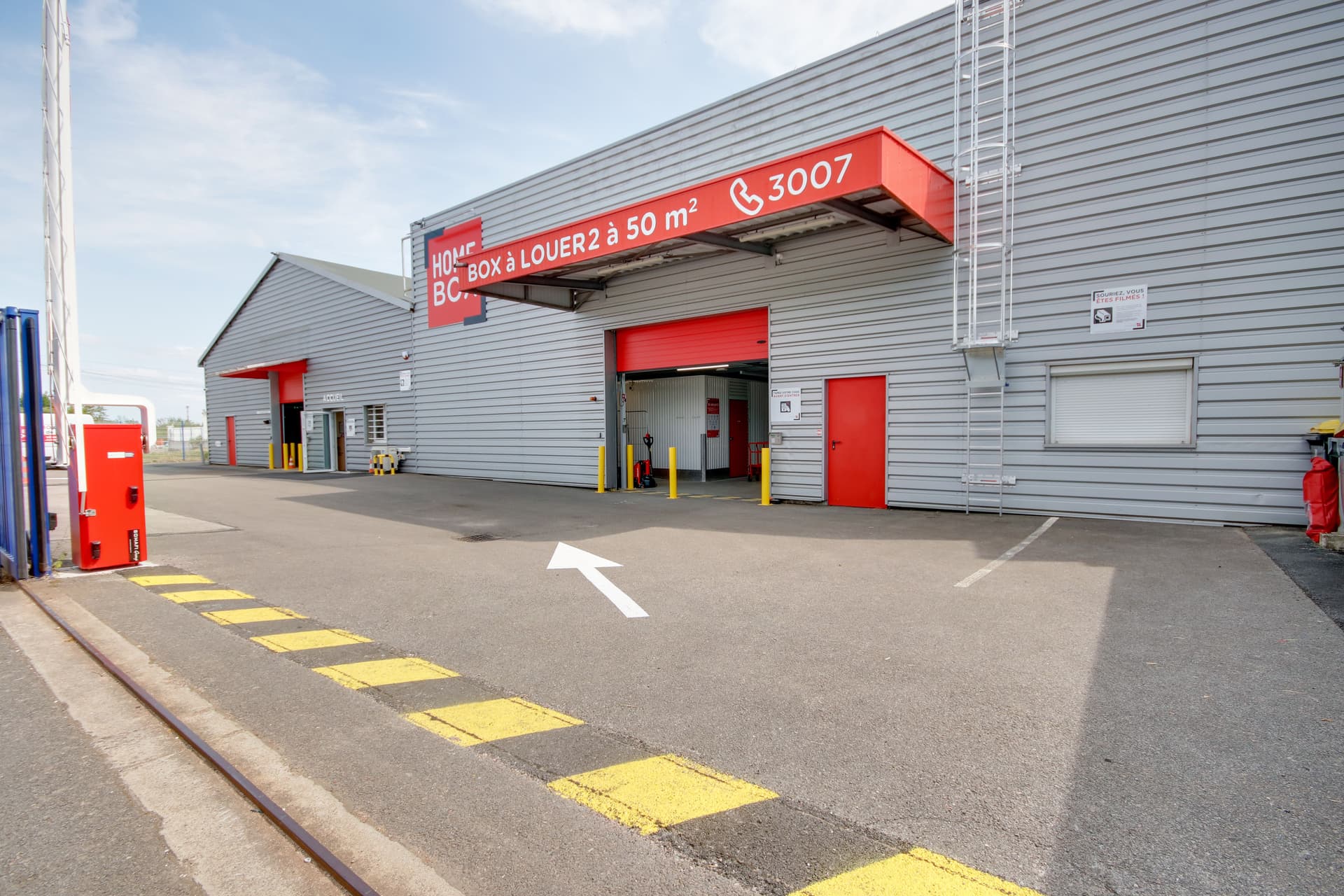 Façade du centre HOMEBOX Dijon, 4 impasse Édouard Belin à Chenôve, avec grande porte rouge.