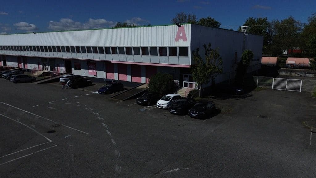 Vue aérienne du bâtiment blanc et rose avec parking et lettre A en façade, HOMEBOX Toulouse Fondeyre, 8 avenue Fondeyre à Toulouse