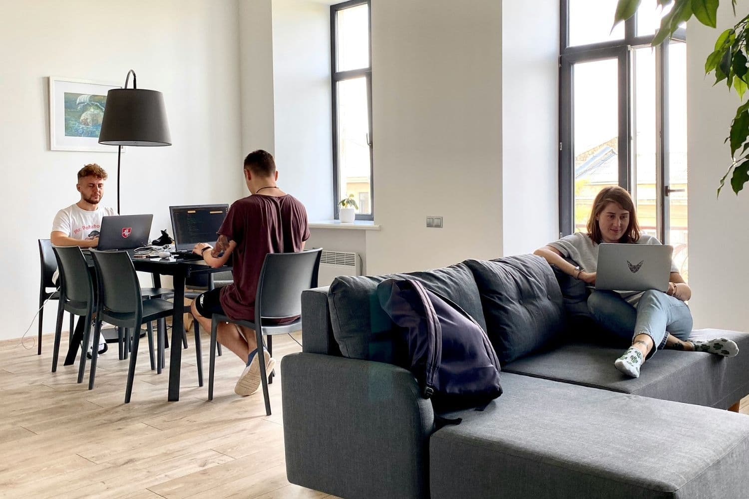 Trois jeunes personnes en colocation dans un grand appartement, occupées sur des ordinateurs