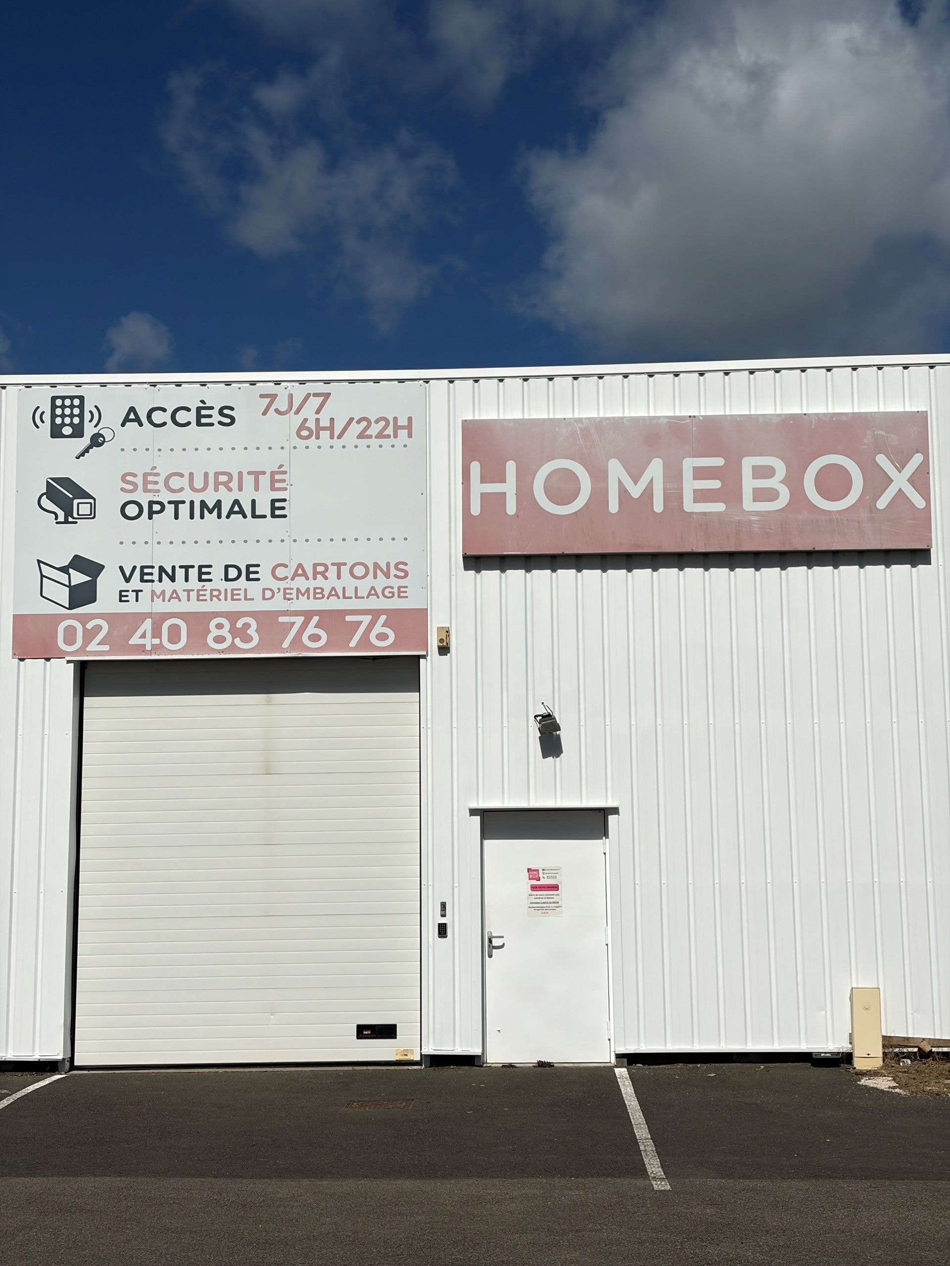 Façade blanche avec signalétique horaires d'accès et sécurité du centre HOMEBOX Ancenis, 225 boulevard de la Prairie à Saint Gereon