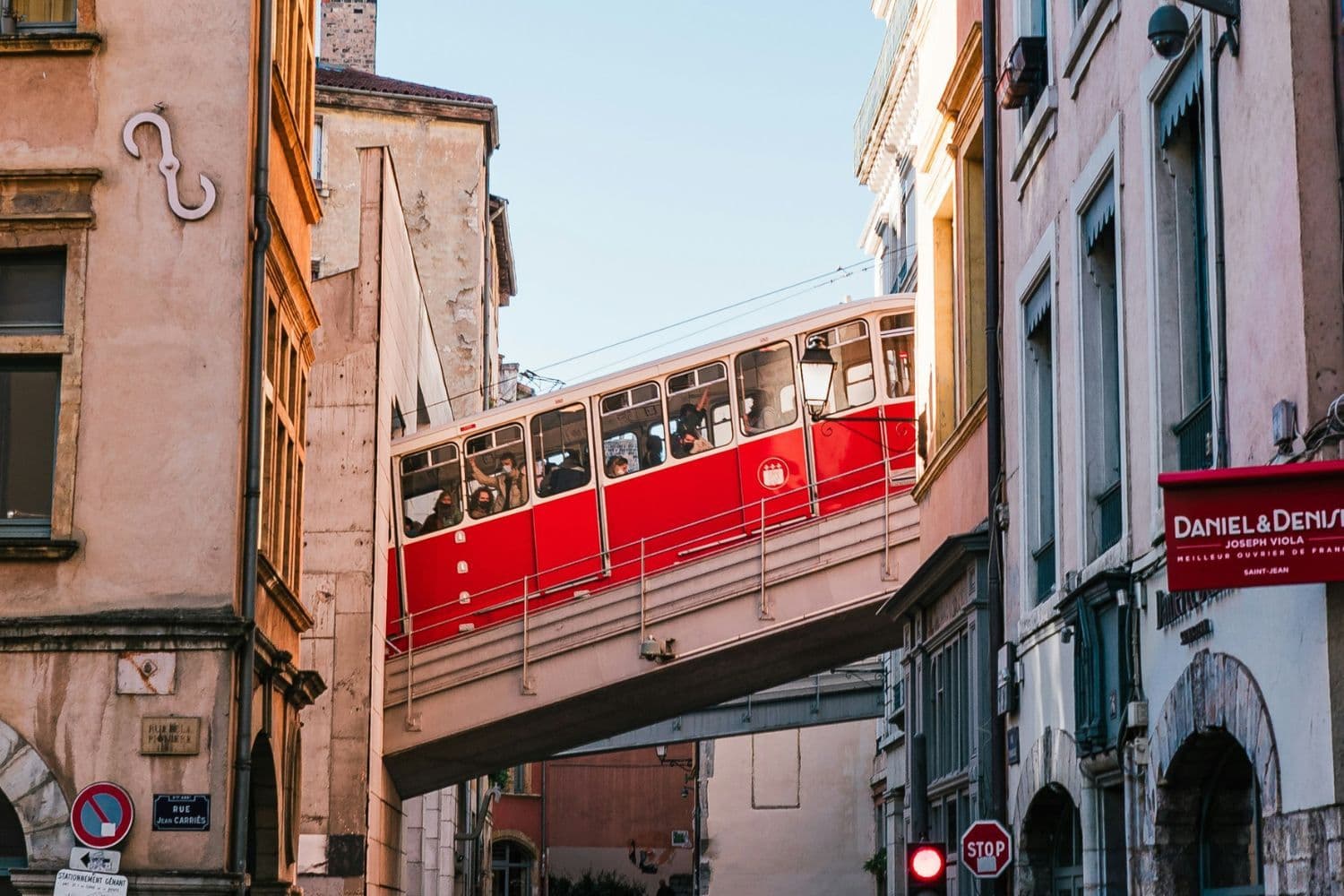 Funiculaire rouge passant entre deux immeubles par beau temps