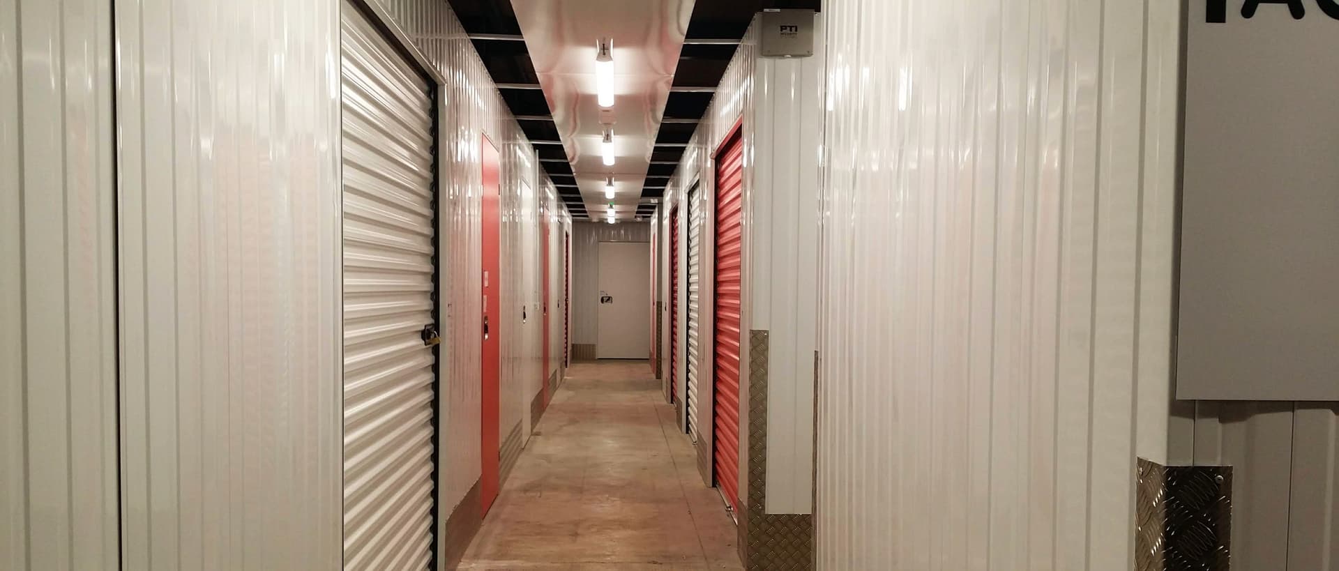 Couloir intérieur avec portes de boxes blanches et rouges du centre HOMEBOX Romilly-sur-Seine