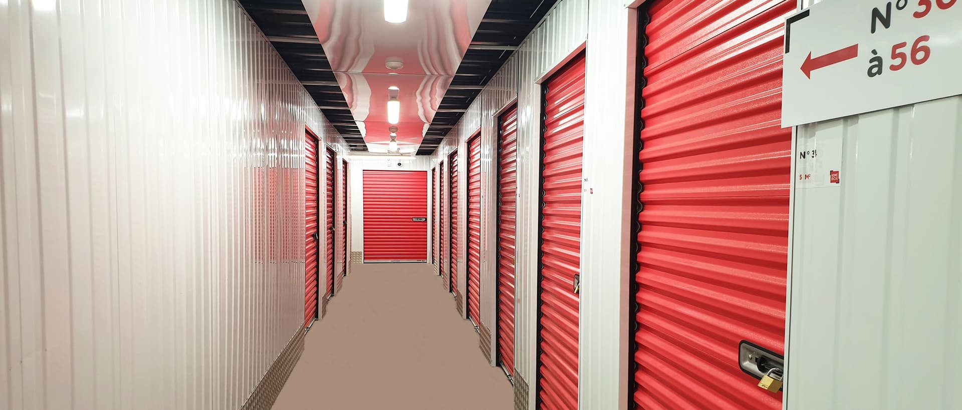 Couloir intérieur du centre HOMEBOX Bagnolet avec portes de box rouges numérotées.