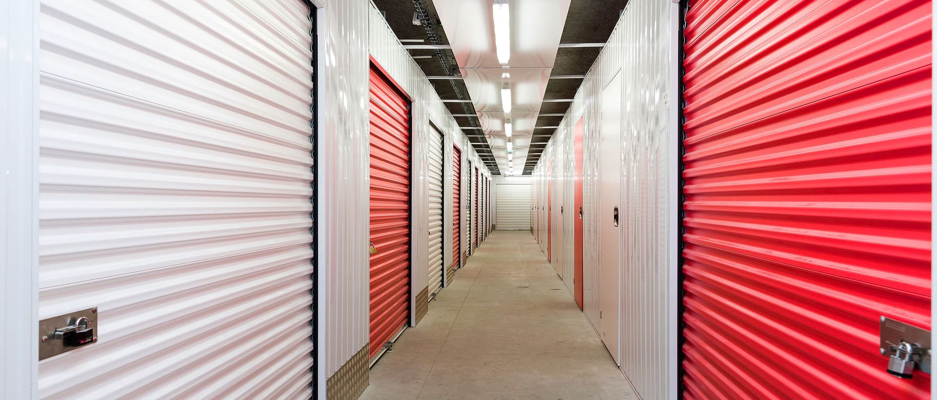 Couloir intérieur avec rangées de portes de boxes rouges et blanches du centre HOMEBOX Paris Porte de Bagnolet