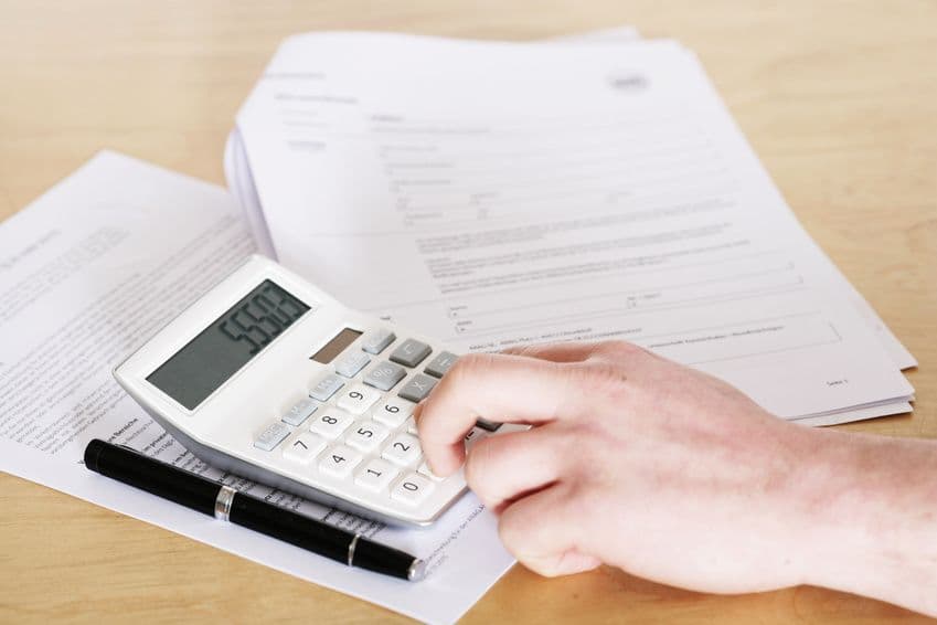 Main utilisant une calculatrice posée sur des documents pour estimer un budget de déménagement