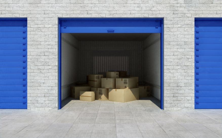 Box de self-stockage ouvert rempli de cartons de déménagement entre deux portes bleues