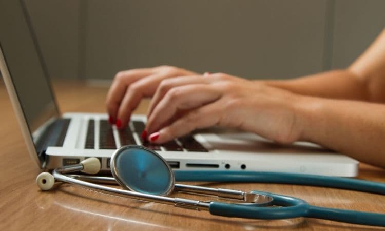 personne tapant à l’ordinateur avec un stéthoscope