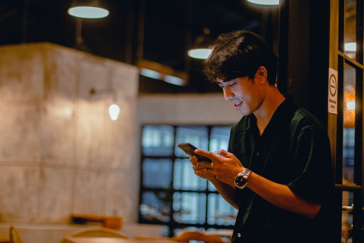 personne en noir envoyant un message depuis son smartphone