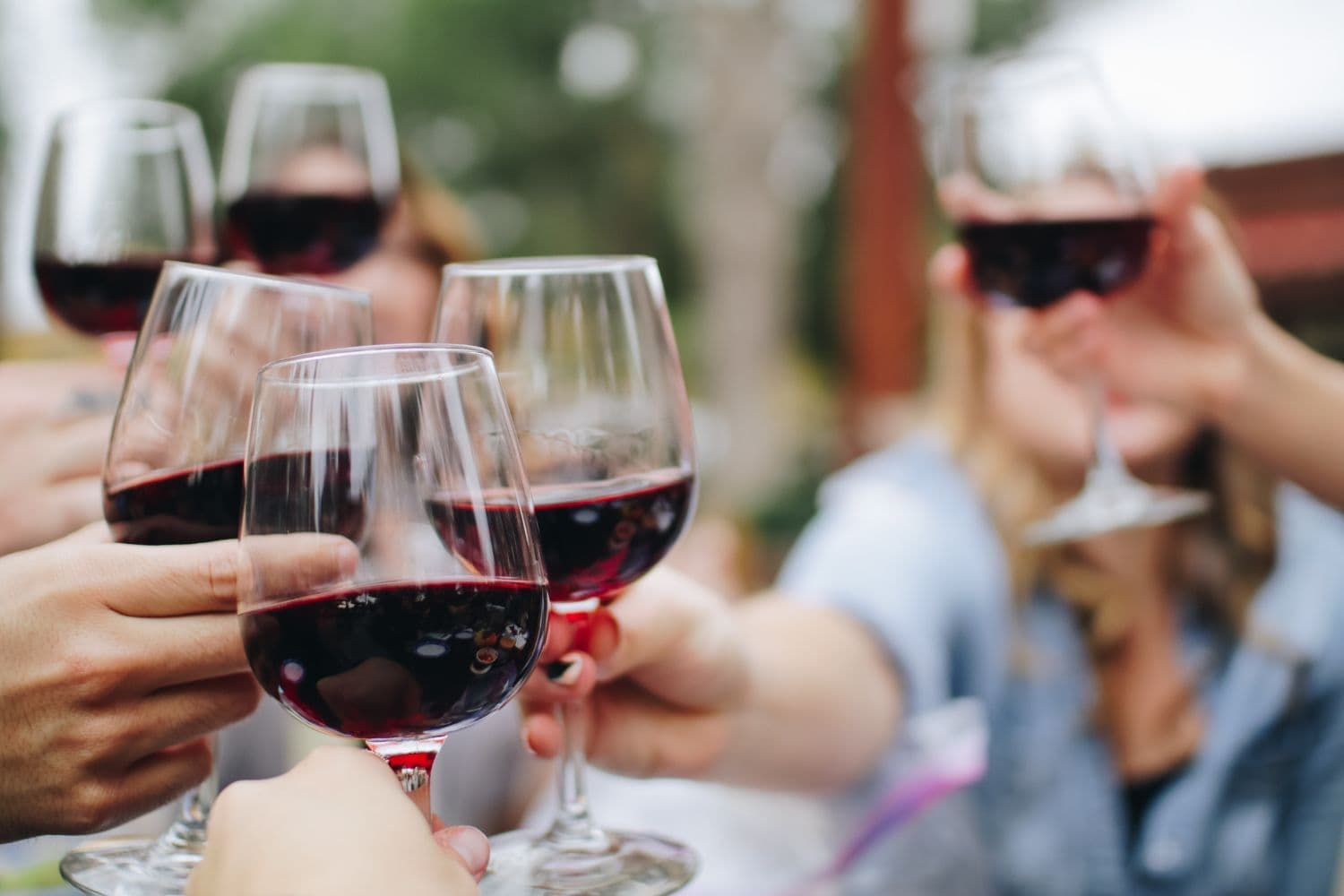 Personnes trinquant avec des verres de vin rouge