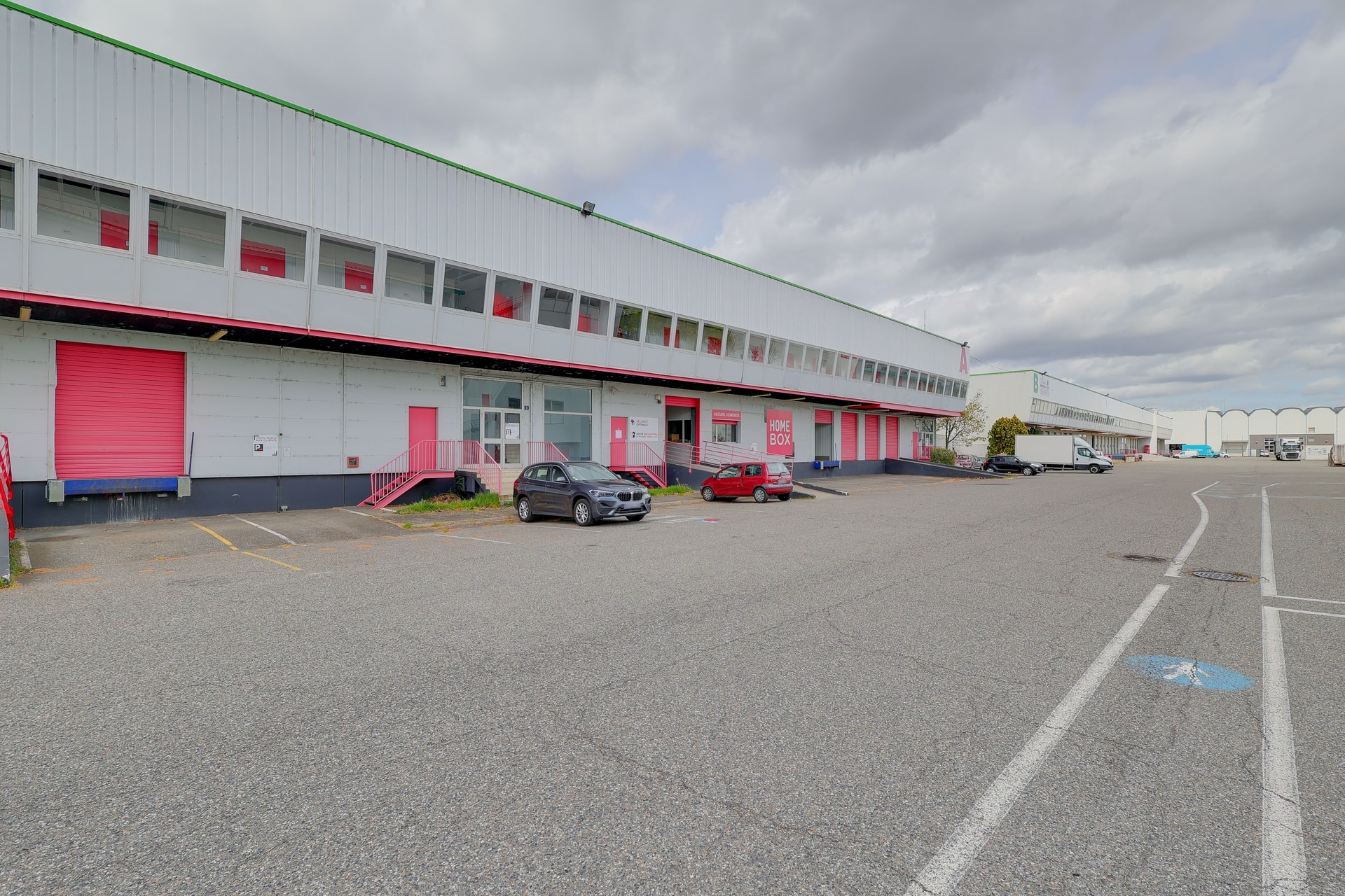 Façade extérieure du bâtiment avec parking, rideaux roses et accès clients, HOMEBOX Toulouse Fondeyre, 8 avenue Fondeyre à Toulouse