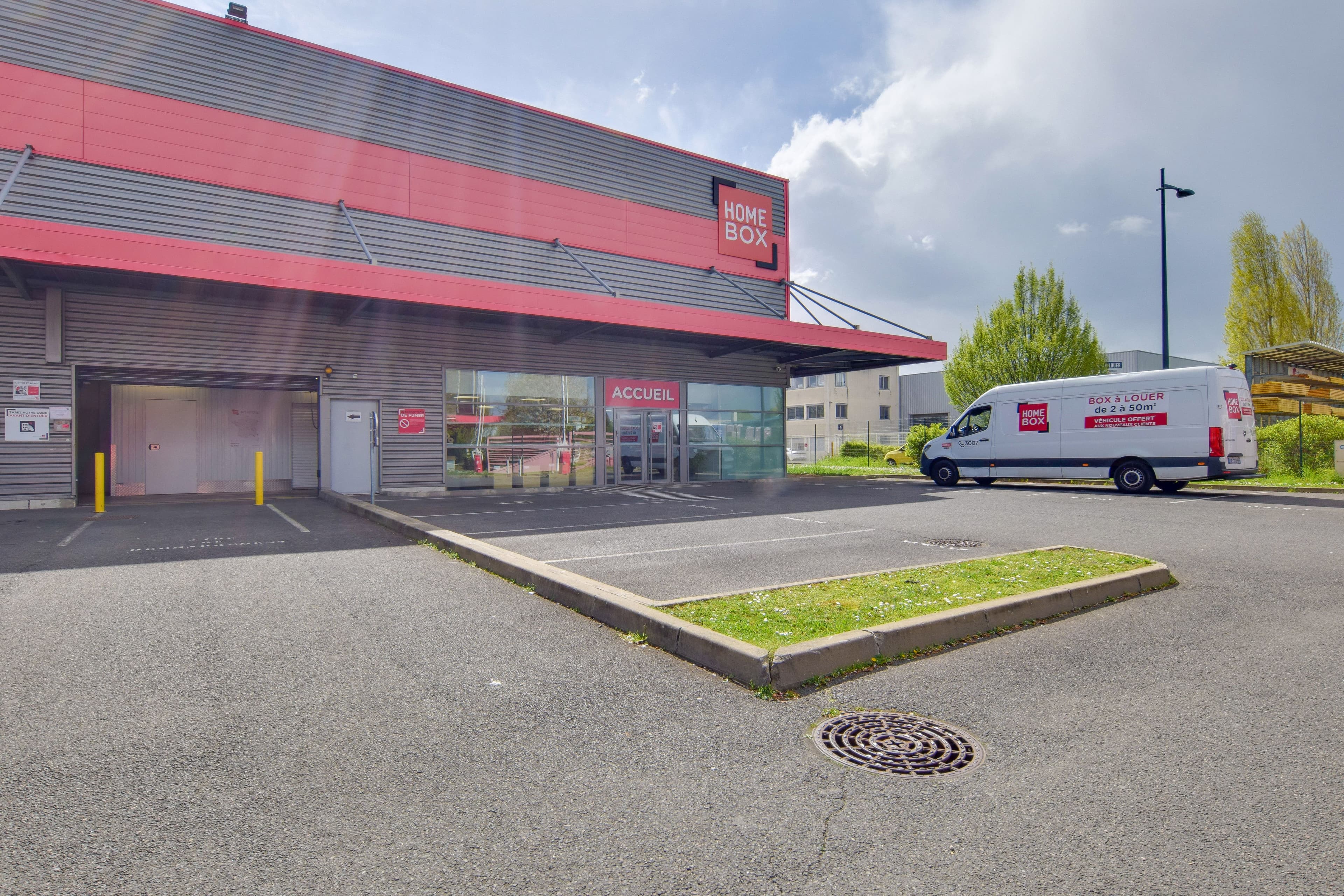 Façade avec vitrine d’accueil et camionnette garée devant le centre HOMEBOX Évry-Courcouronnes.