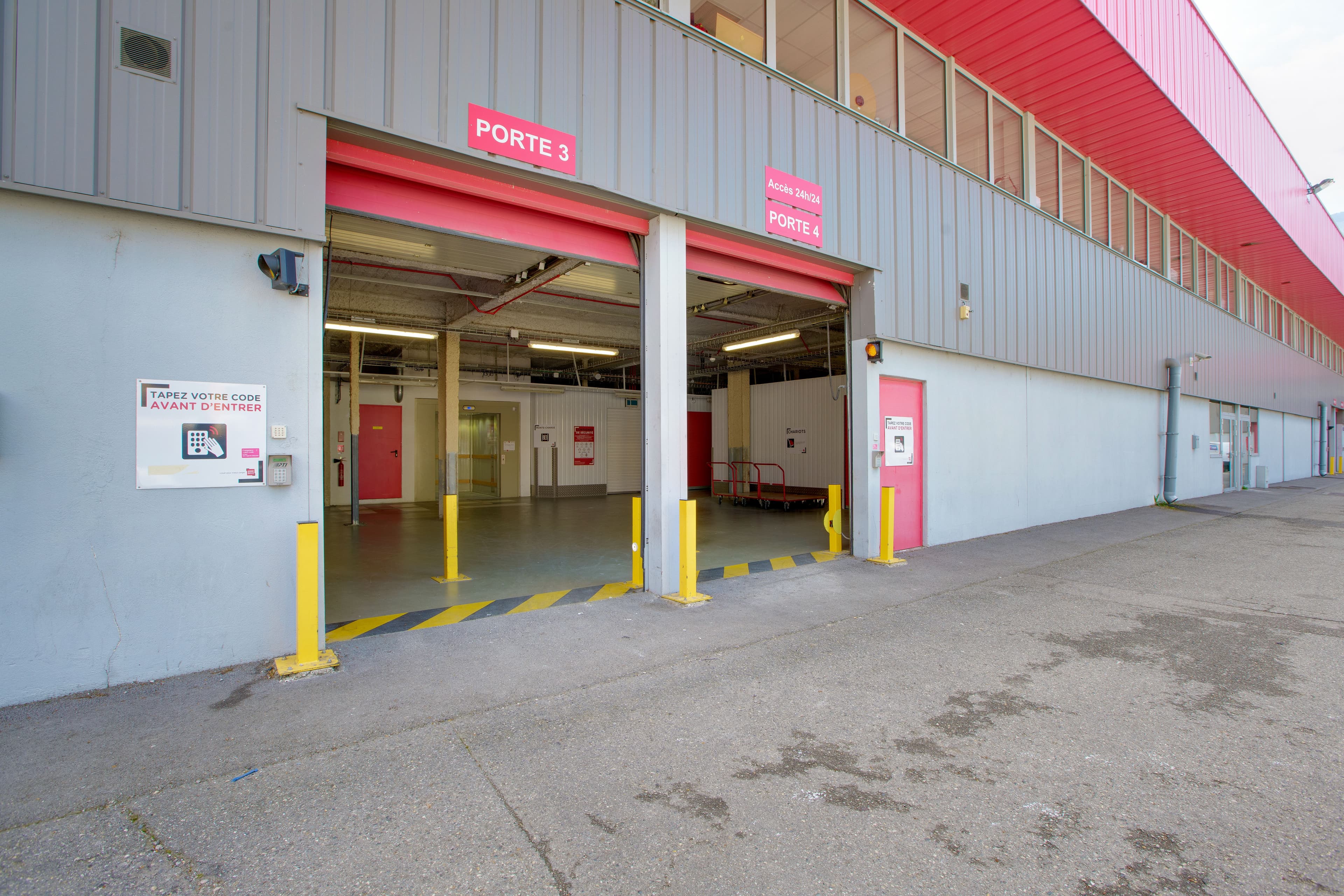 Entrée du centre HOMEBOX Grenoble avec deux portes roulantes rouges signalées Portes 1 et 2.