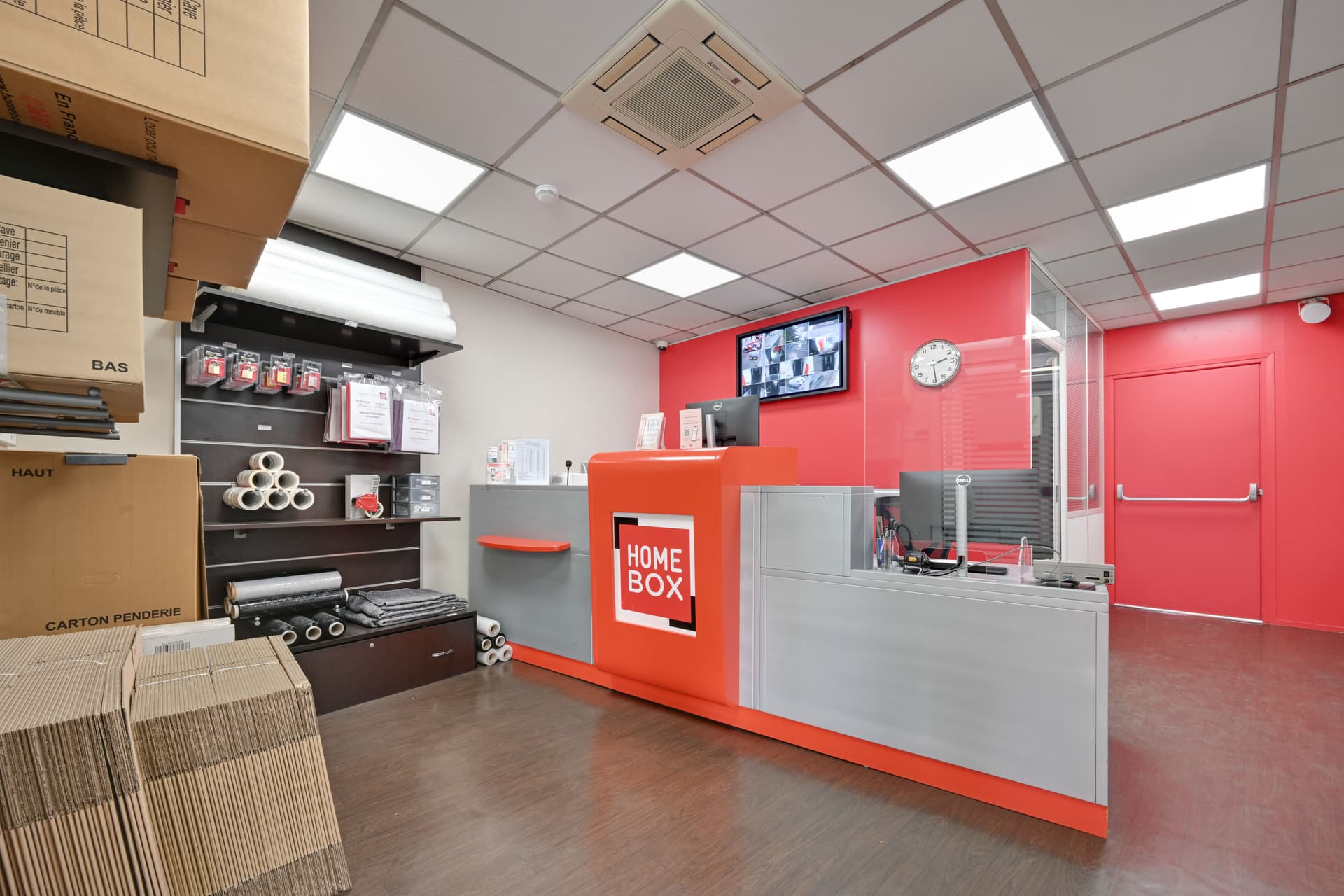 Espace accueil moderne avec comptoir orange et gris et présentoirs de cartons de déménagement du centre HOMEBOX Paris Porte de Bagnolet