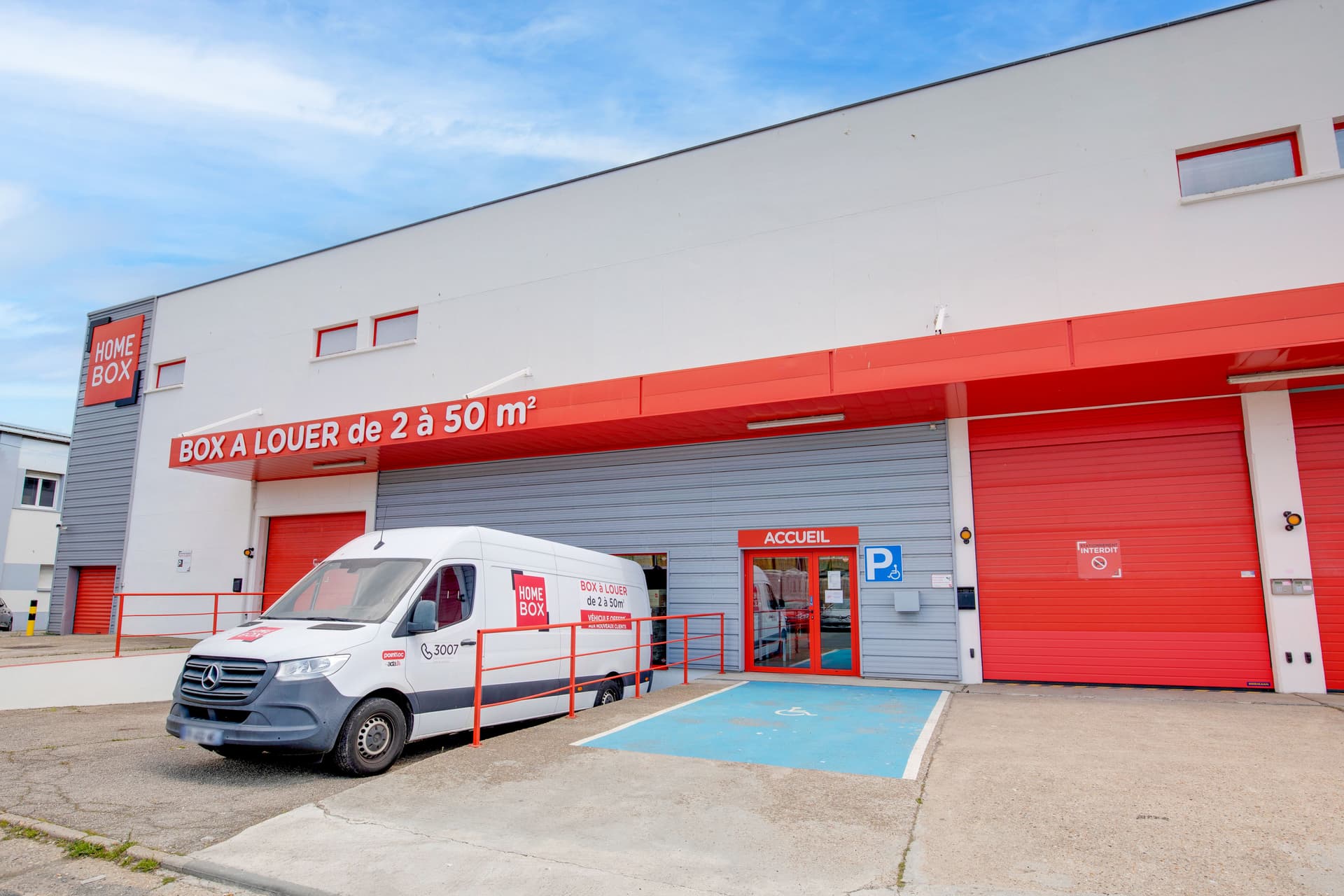 Façade extérieure avec camion HOMEBOX garé devant l'accueil et place handicapée bleue, HOMEBOX Le Havre, 26 rue d'Iena à Le Havre