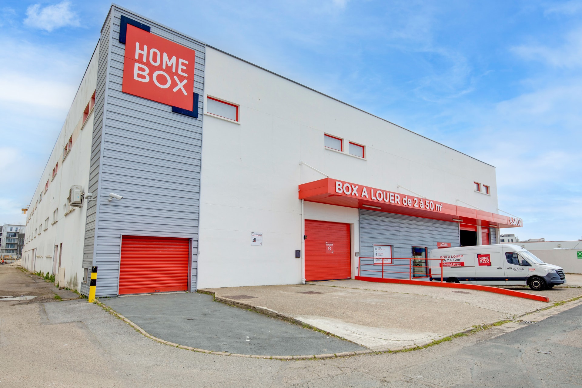 Façade extérieure blanche et grise avec enseigne HOMEBOX, boxes rouges et camion utilitaire, HOMEBOX Le Havre, 26 rue d'Iena à Le Havre