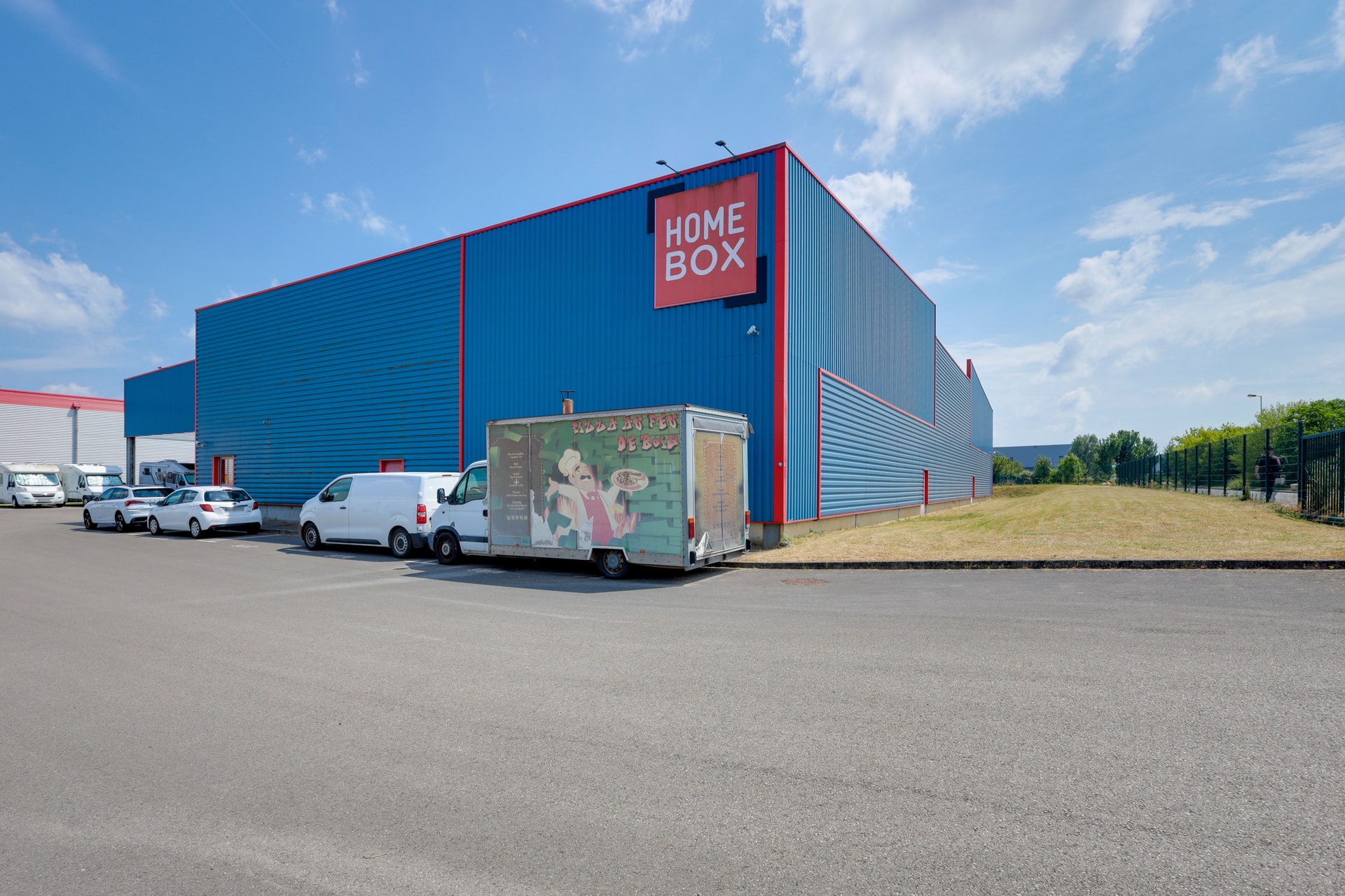 Façade bleue avec logo HOMEBOX et camion sur le parking, HOMEBOX Nanteuil - Dammartin, Allée des Primevères à Nanteuil - Le - Haudoin