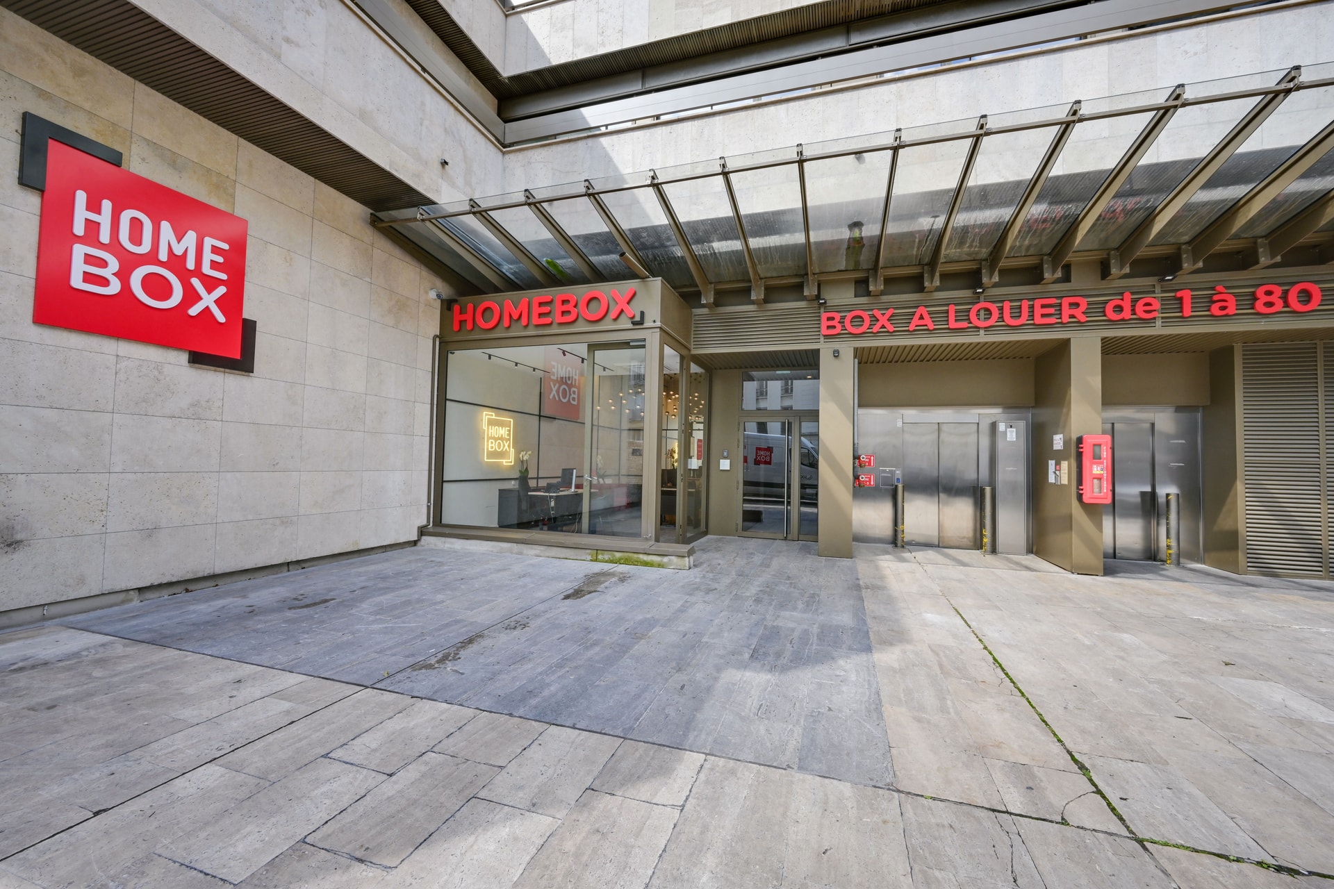 Entrée vitrée moderne sous auvent avec enseigne lumineuse, HOMEBOX Paris 16, 11 rue Piccini à Paris