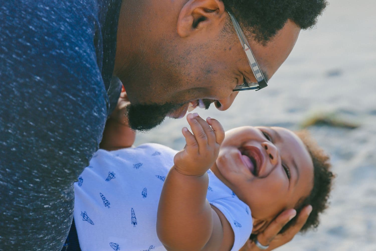 Père avec son bébé souriant dans les bras