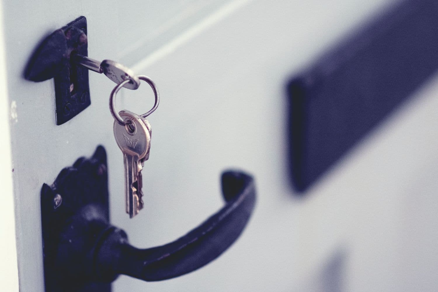 Clés dans la serrure d’une porte blanche à poignée noire