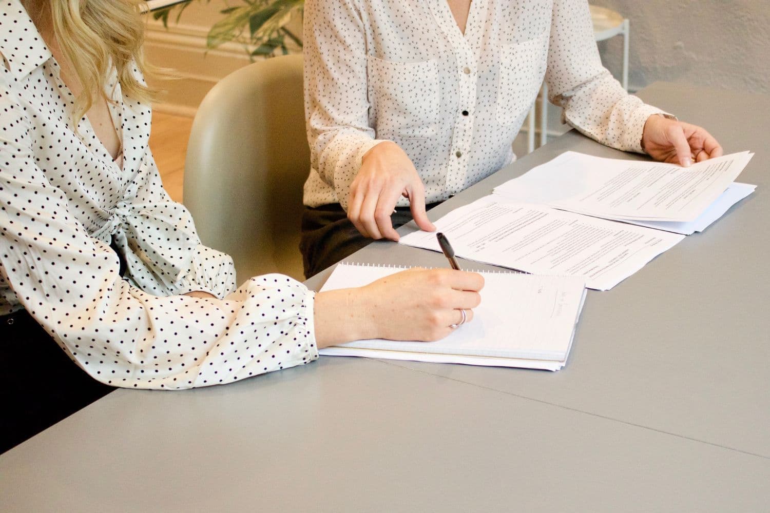 Une personne tenant une liasse de document, une autre prenant des notes