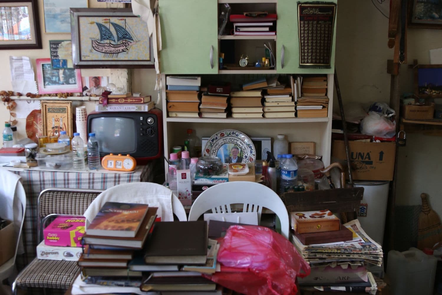 Pièce très encombrée avec des piles de livres sur une table et des étagères