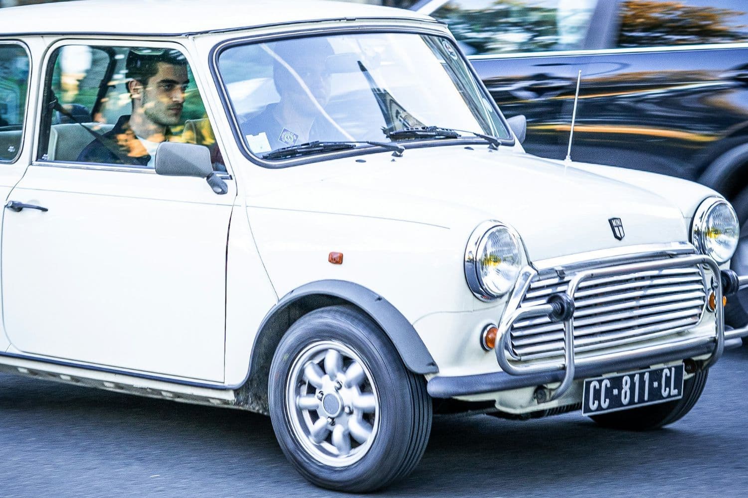 Deux personnes dans une petite voiture blanche ancienne