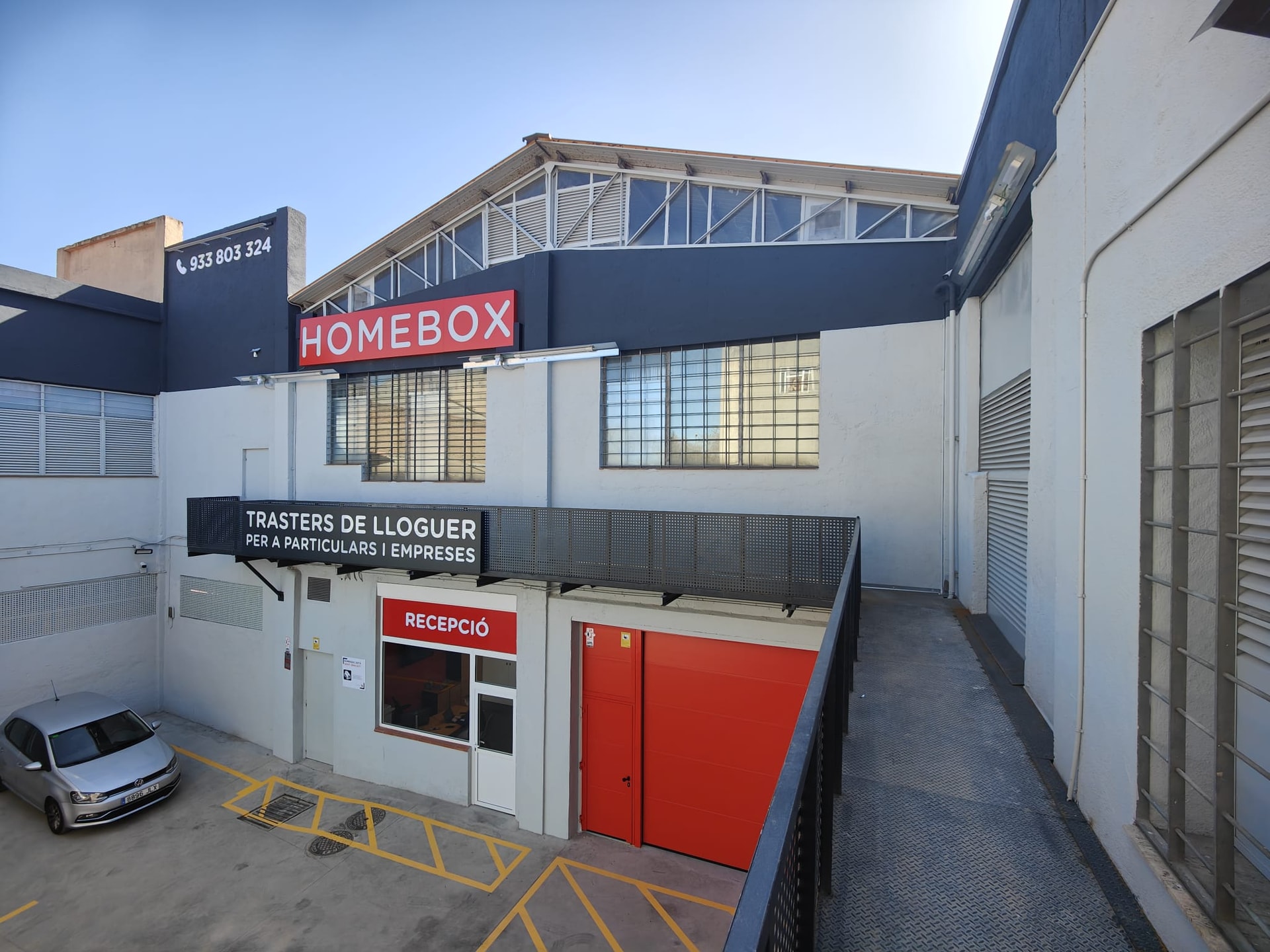 Façade et entrée du centre HOMEBOX Barcelona - Sant Andreu, Carrer Sant Adrià, avec porte rouge et enseigne.