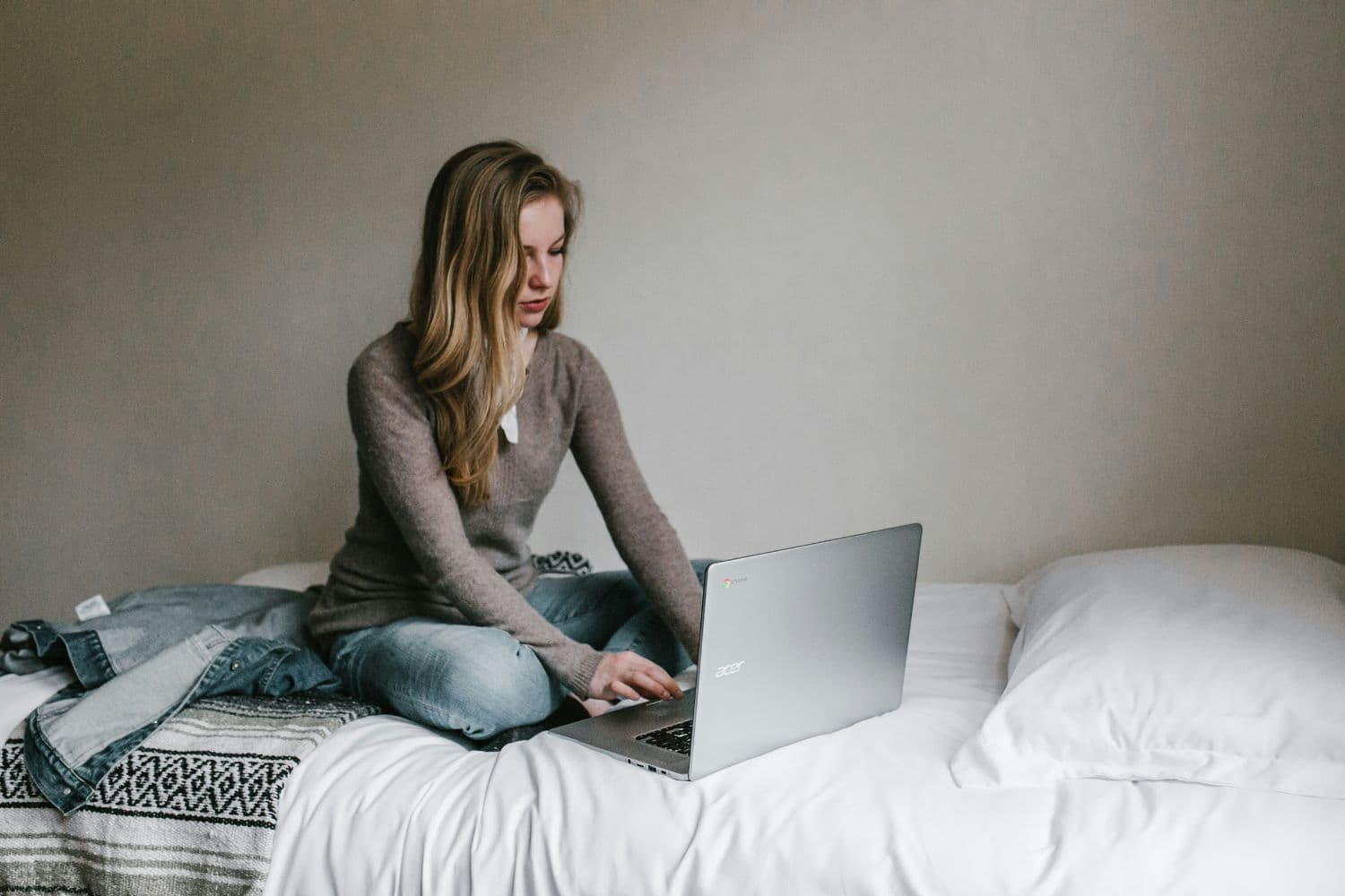 Personne utilisant un ordinateur sur un lit à draps blancs