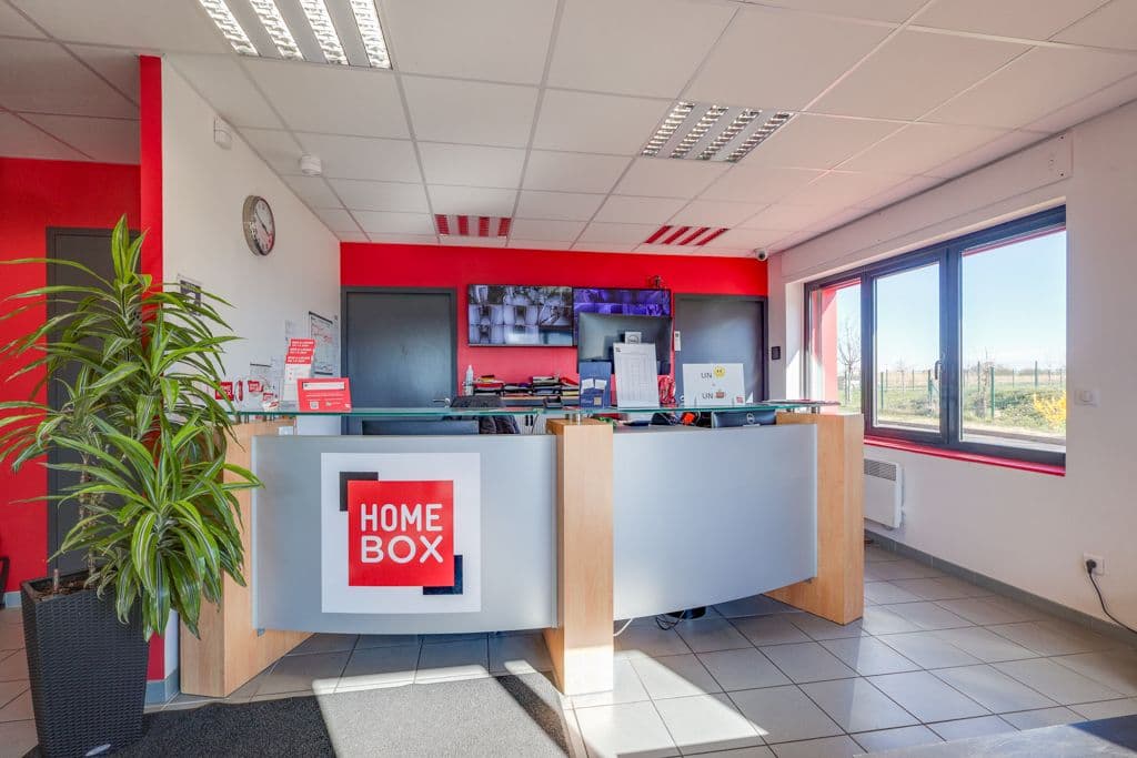 Accueil du centre HOMEBOX Carrières-Chanteloup avec comptoir moderne et écrans de vidéosurveillance.