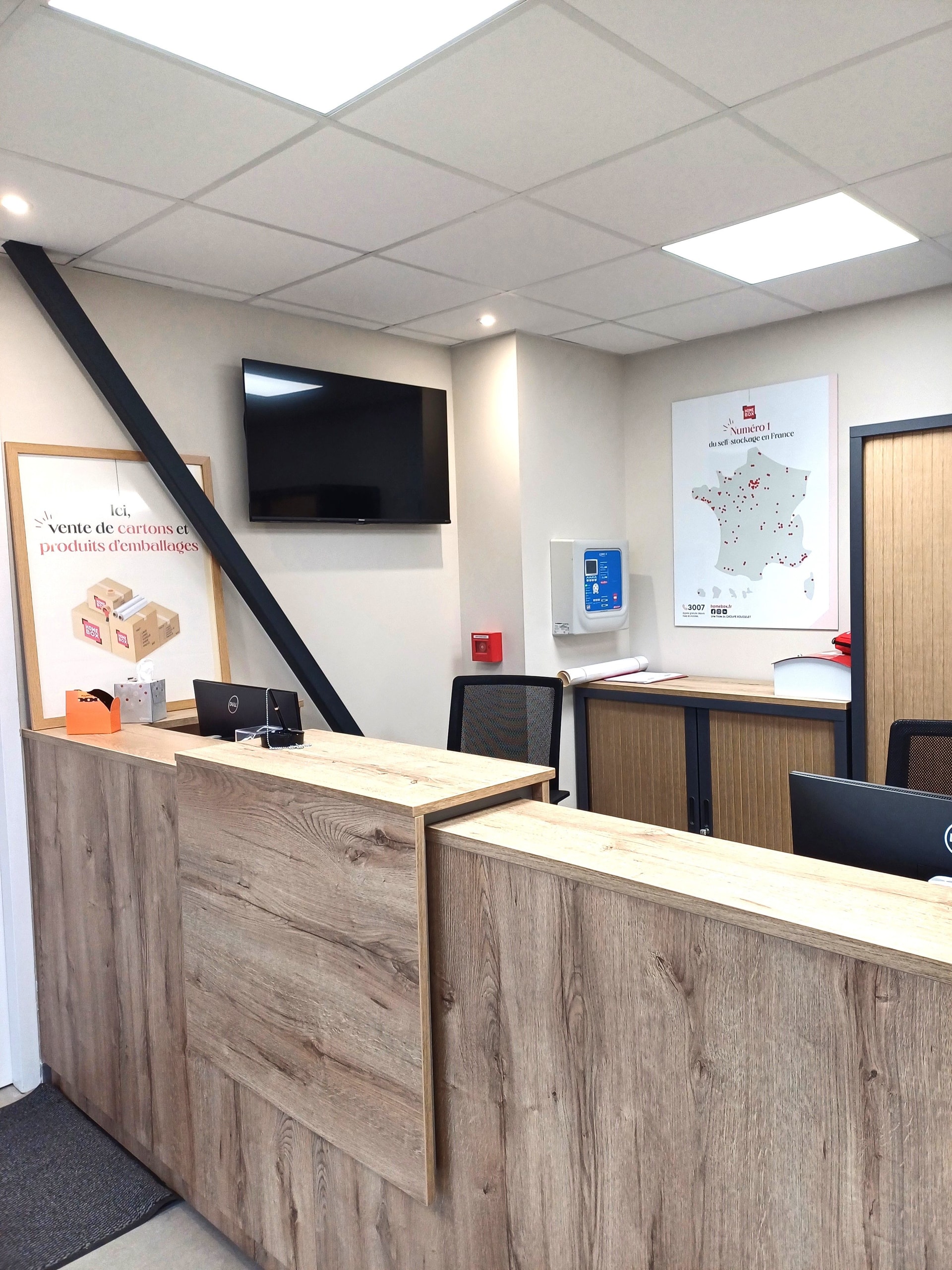 Accueil avec comptoir bois et écran mural au centre HOMEBOX Cherbourg.