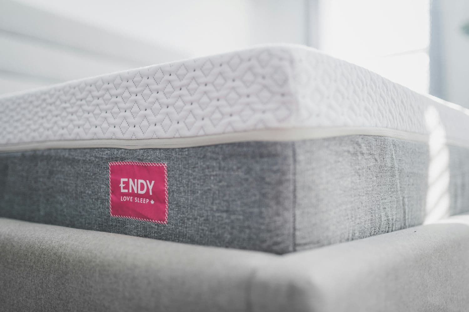 Gros plan sur le coin d’un matelas blanc et gris perle