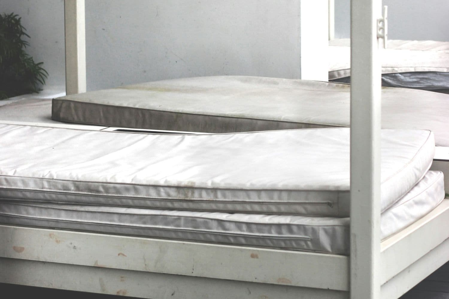 Deux matelas blancs sales empilés sur un lit blanc et sale lui aussi