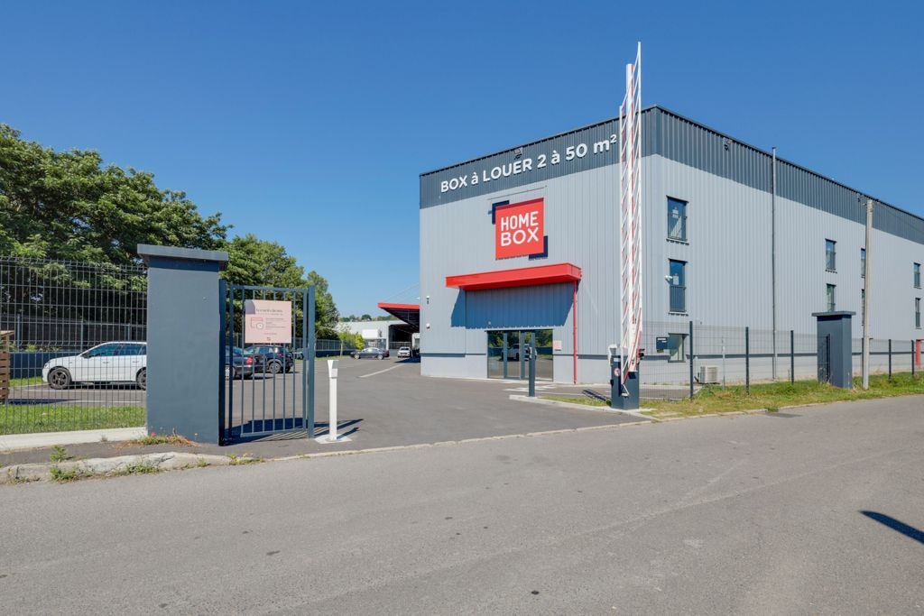 Bâtiment gris avec enseigne HOMEBOX et portail d'entrée sous ciel bleu, HOMEBOX Saint-Ouen-l'Aumône, 1 Rue des Préaux à Saint-Ouen-l'Aumône