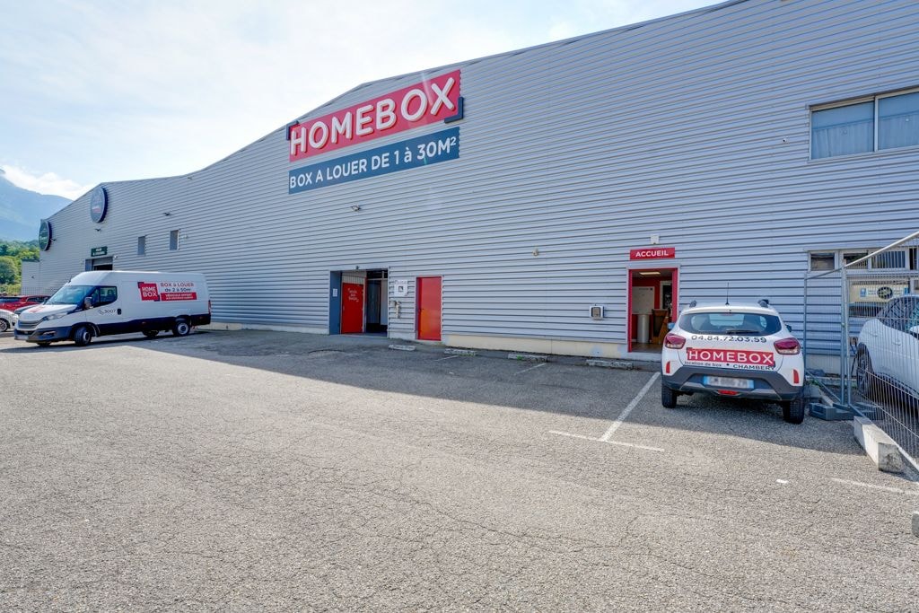 Façade du centre de self-stockage HOMEBOX Chambéry avec parking et véhicules devant l’entrée