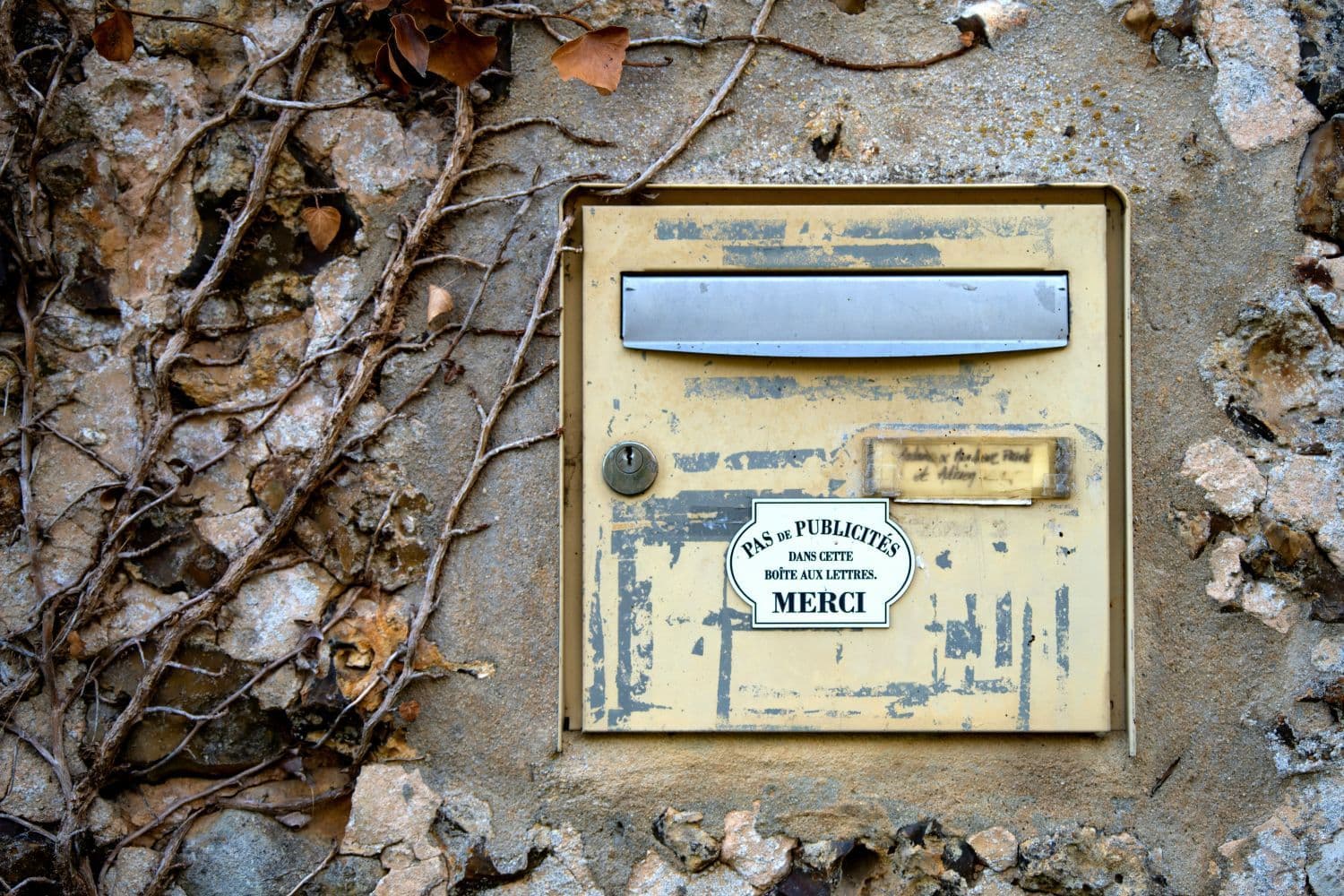 Vieille boîte aux lettres jaune dans un mur en pierres
