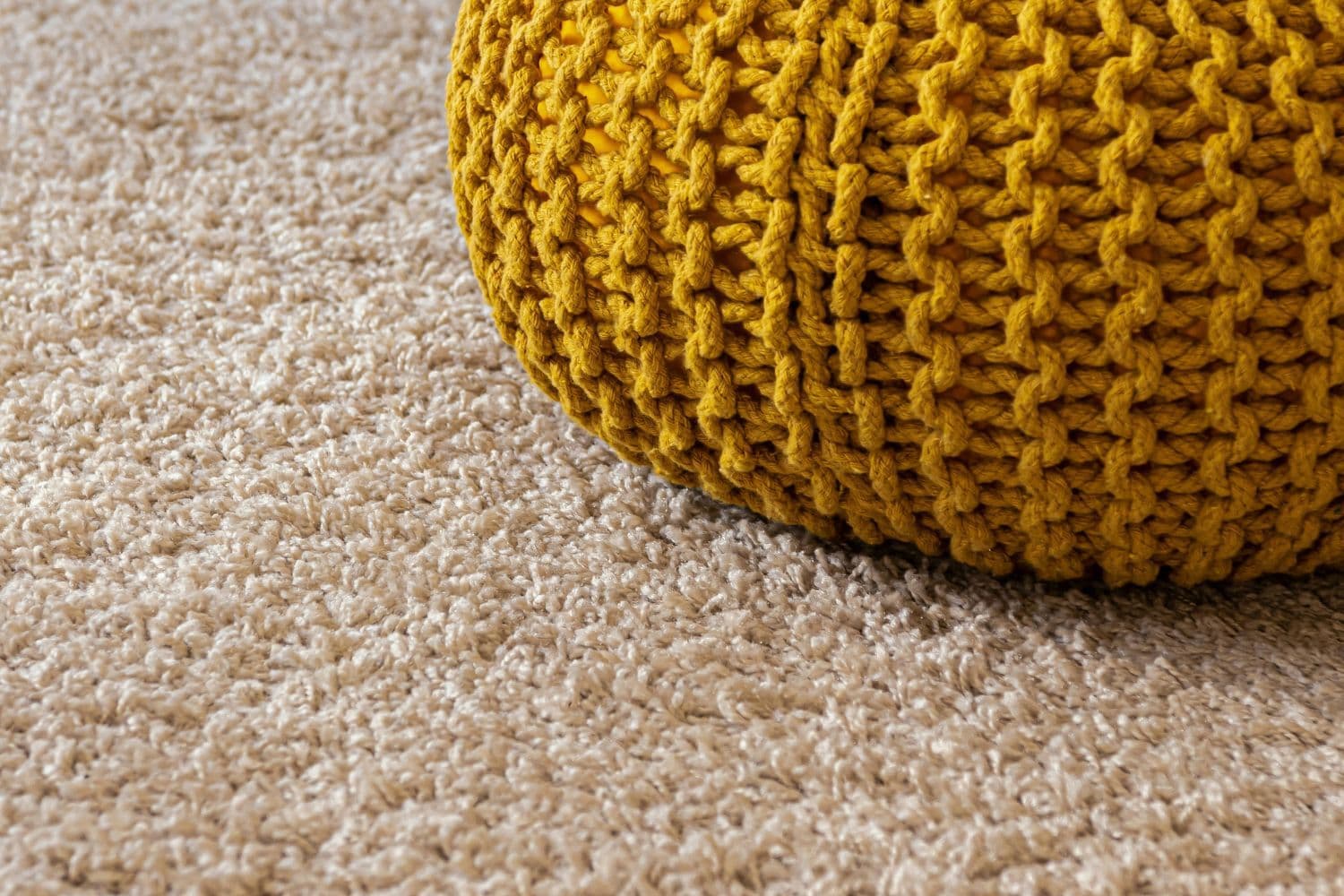 Pouf jaune tricoté sur un tapis beige