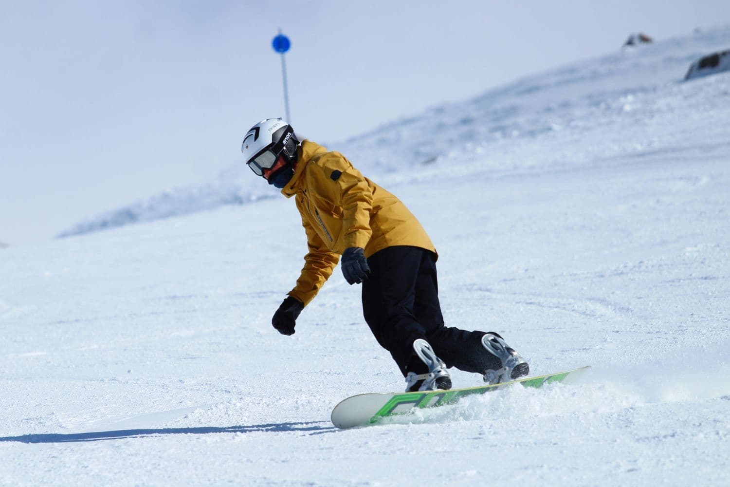 Snowboarder sur la piste avec un manteau jaune et un pantalon noir