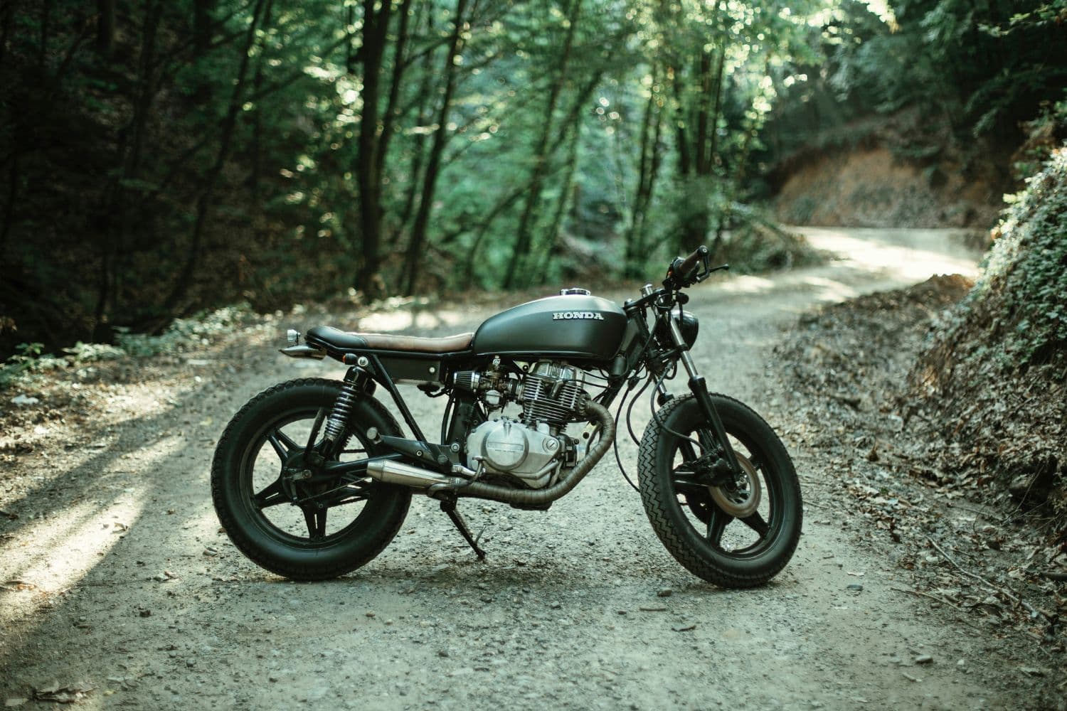 Moto stationnée au milieu d’un chemin forestier