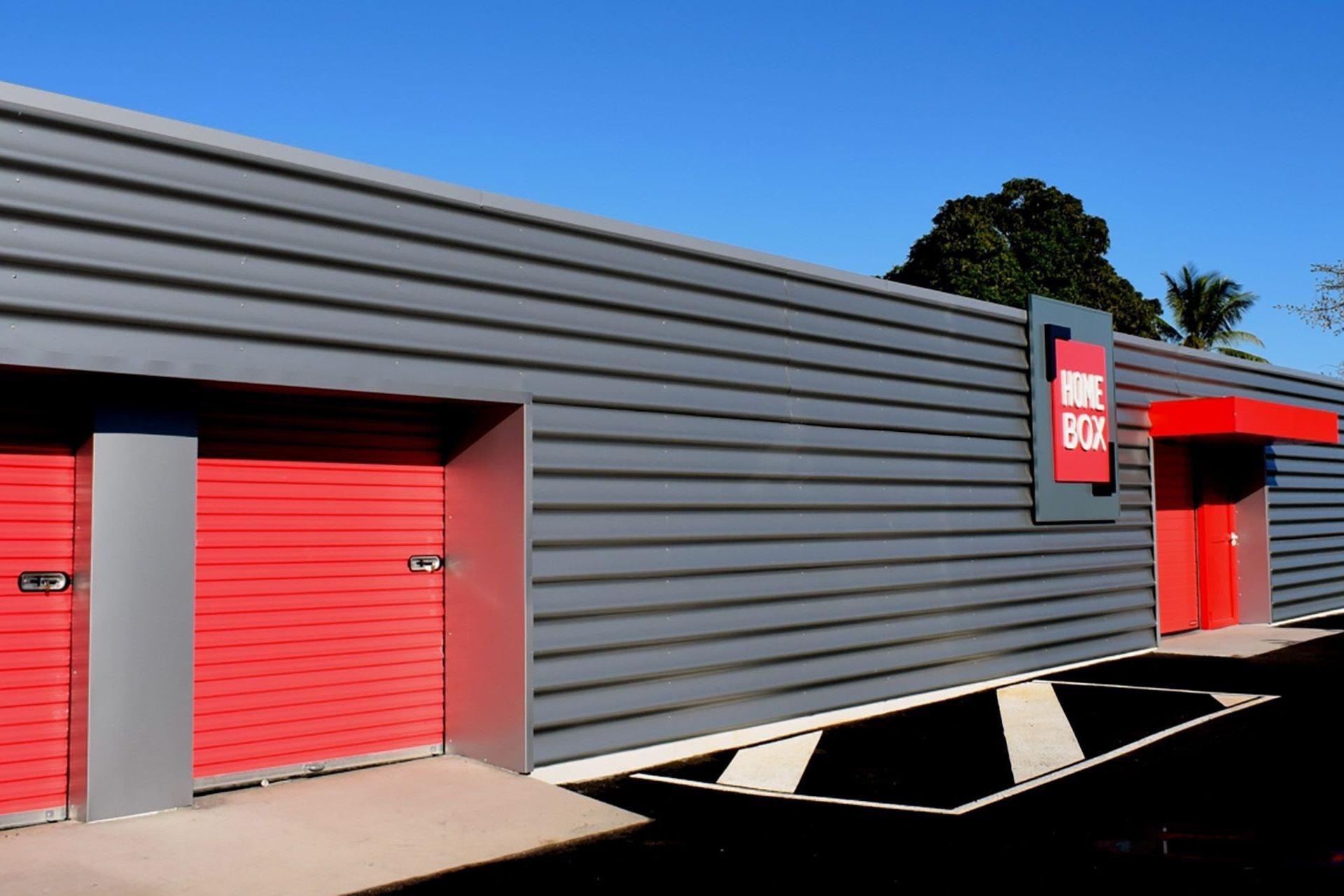 Façade grise avec rideaux rouges et enseigne sous ciel bleu, HOMEBOX La Réunion, 40 rue Mahatma Gandhi à La Possession