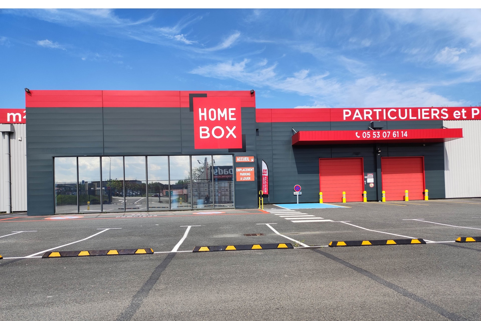 Façade rouge et grise avec enseigne et parking matérialisé, HOMEBOX Périgueux, 18 Rue des Digitales à Trélissac