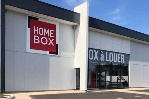 Façade blanche avec entrée vitrée et logo HOMEBOX du centre HOMEBOX Plougoumelen, Rue de l'avenir à Plougoumelen