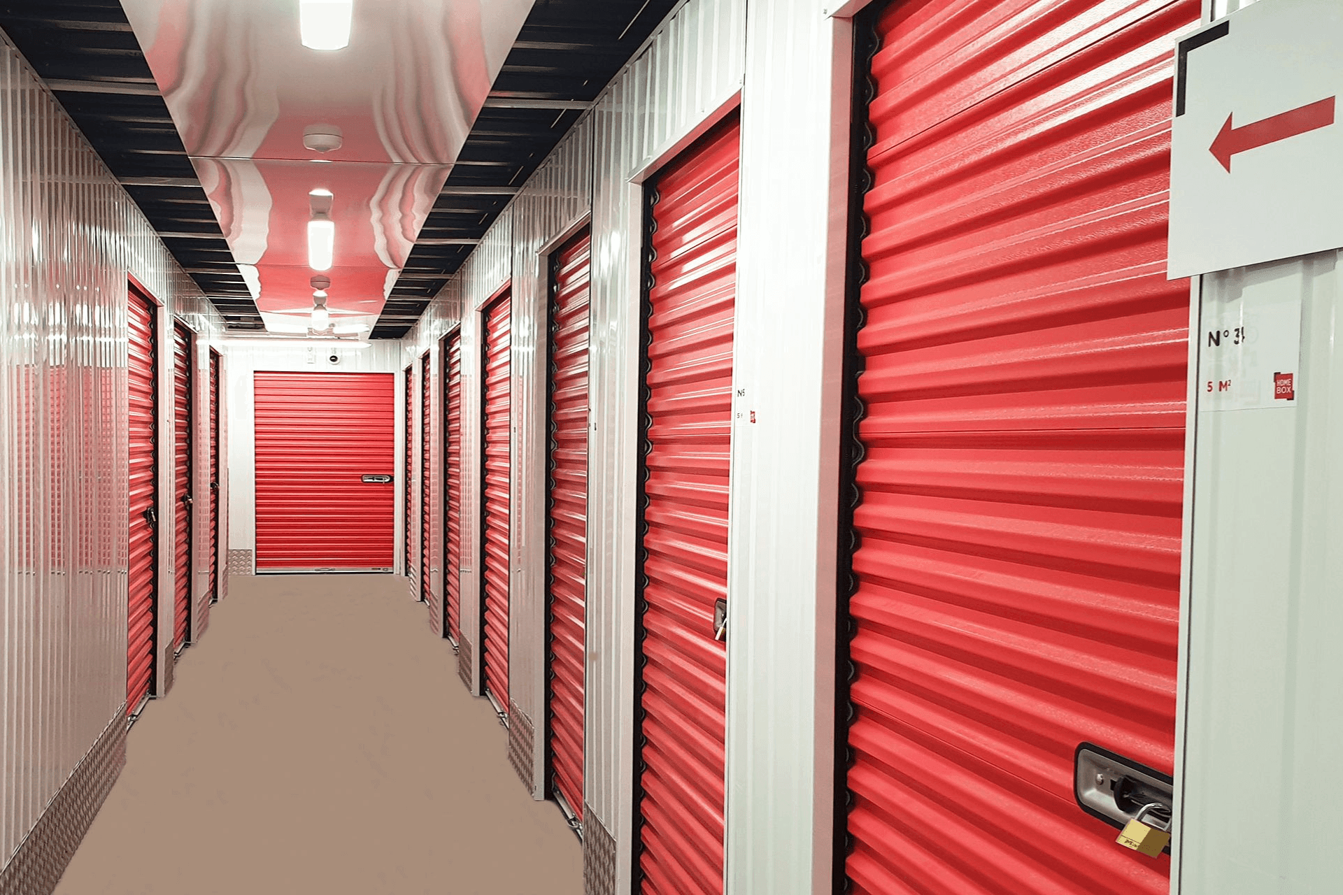 Couloir intérieur du centre de self-stockage HOMEBOX Cébazat avec des box fermés par des portes rouges.