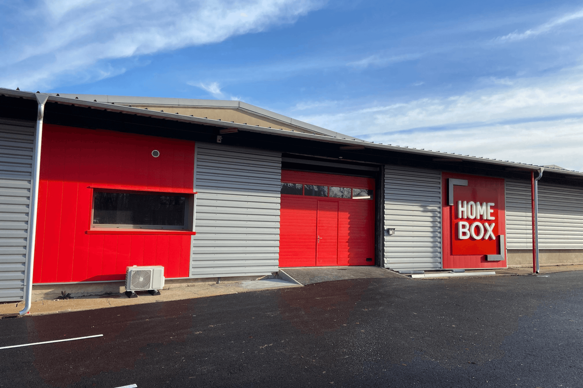 Vue extérieure du centre HOMEBOX Bourges, Allée Napoléon III, avec entrée principale et logo rouge.