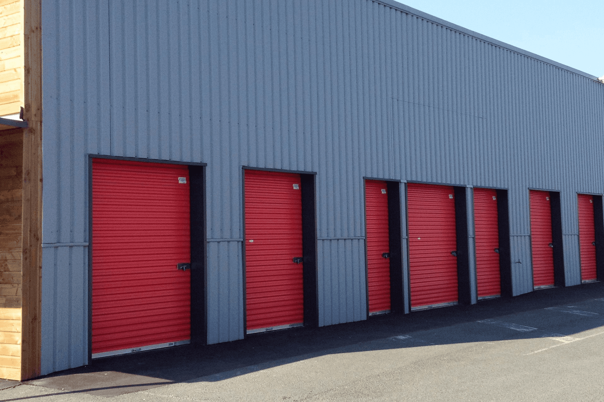 Façade latérale avec portes roulantes rouges au centre HOMEBOX Cholet, 12 avenue de la Marne.