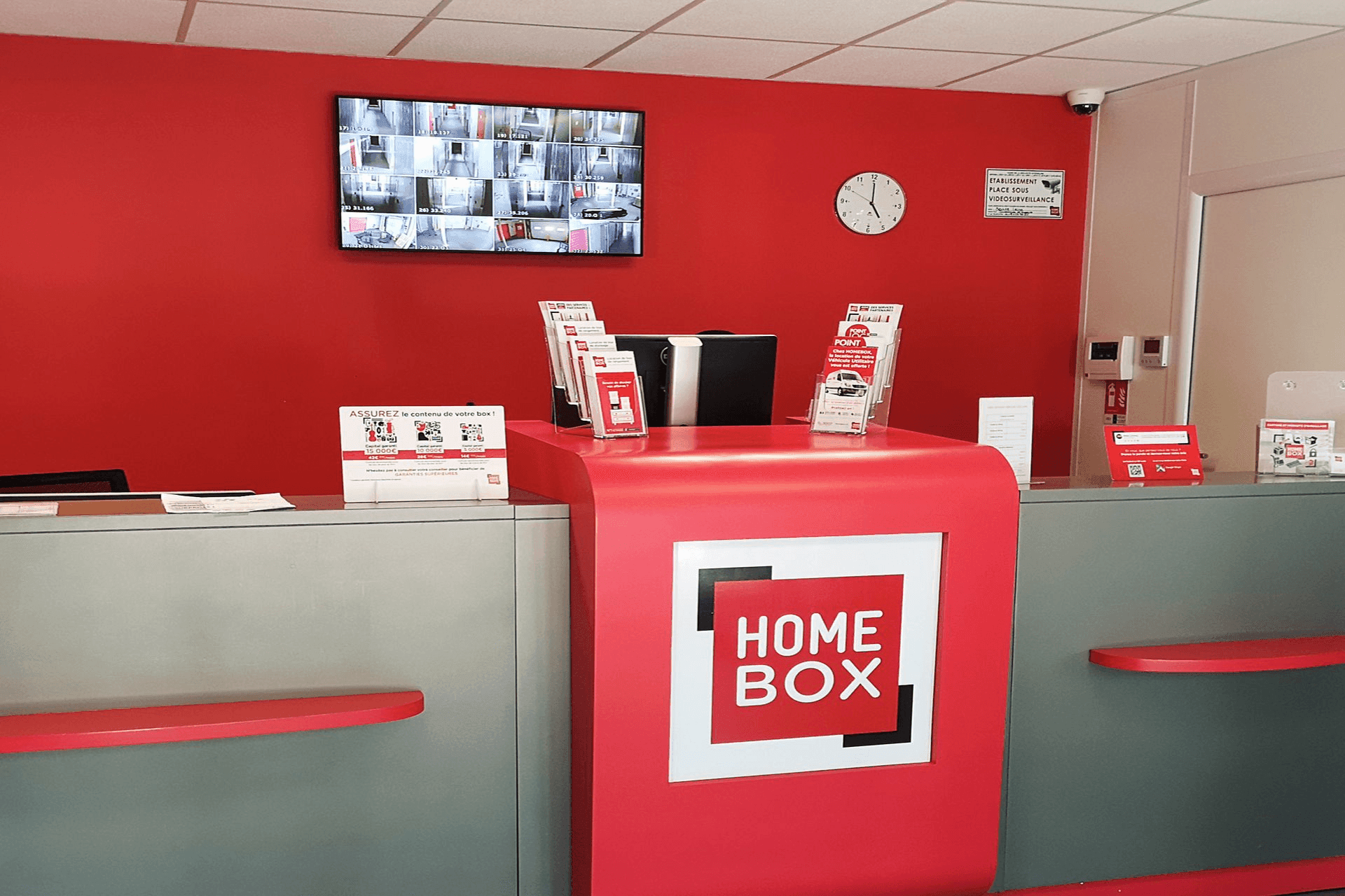 Pupitre d'accueil rouge avec écran de vidéosurveillance du centre HOMEBOX Pornichet La Baule