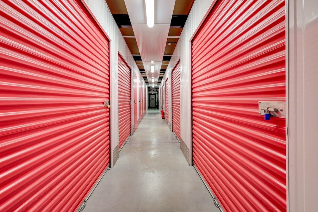 Couloir intérieur du centre HOMEBOX Carrières-Chanteloup avec portes de box rouges alignées.