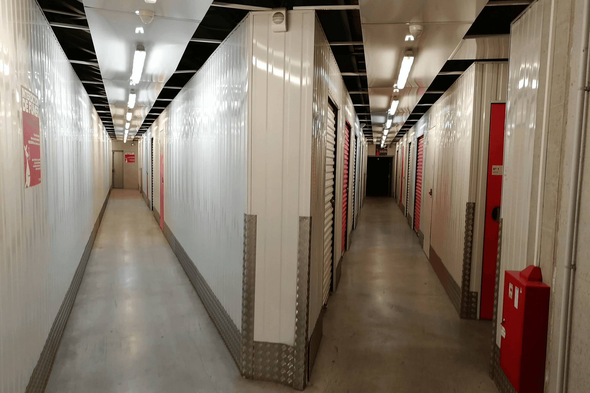 Couloir intérieur avec portes roulantes blanches et rouges au centre HOMEBOX Clermont-Ferrand.