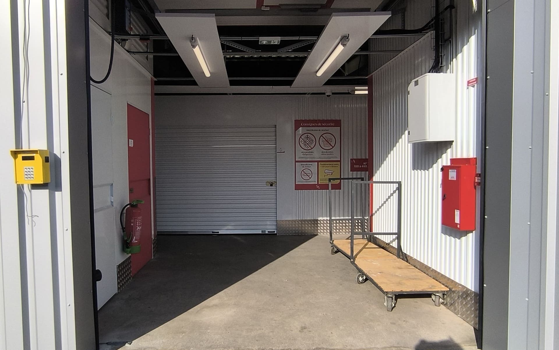 Sas d'entrée intérieur avec chariot de manutention et interphone jaune, HOMEBOX Fontenay-le-Comte